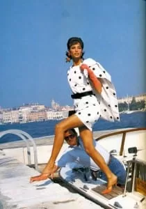 Editorial vintage: modelo con vestido de lunares blanco y negro posa en un barco frente a Venecia