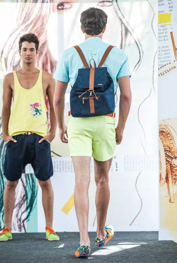 Modelo con camisa azul cielo y morral azul de espaldas junto a otro con camisilla amarilla, Lolos Swimwear en El Cubo