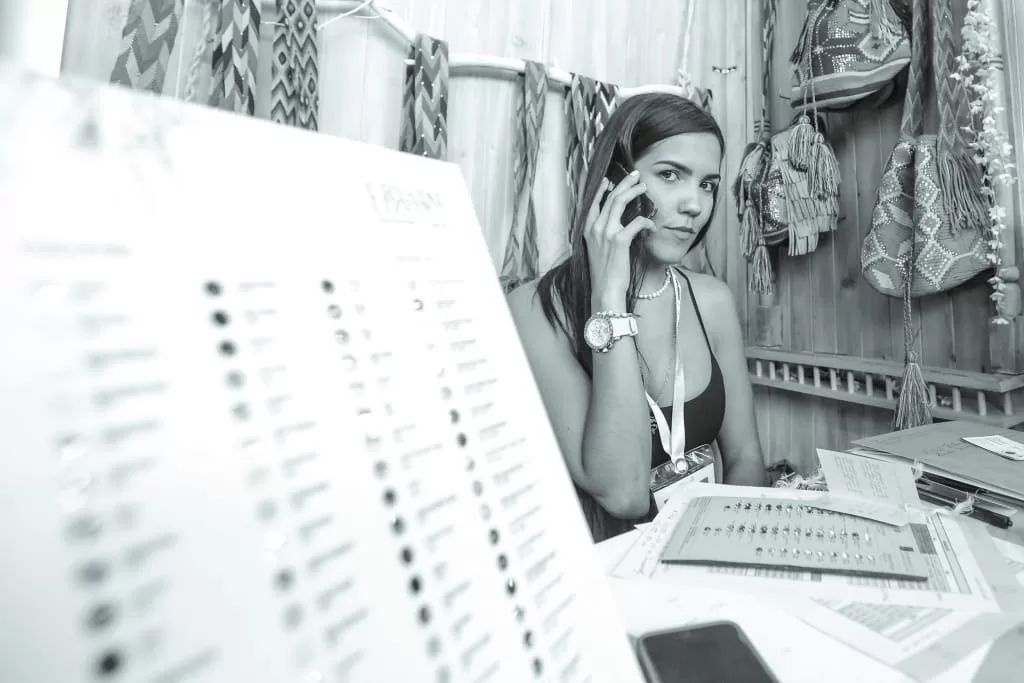 Diseñadora de Caídas del Cielo atiende una llamada en su stand de accesorios tejidos en Colombiamoda 2013, blanco y negro