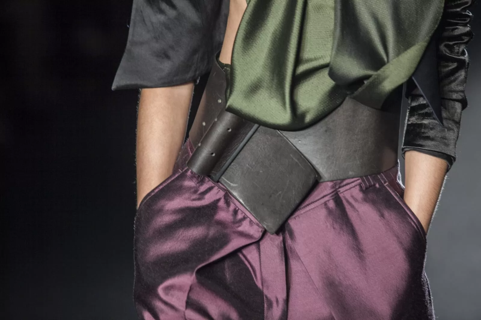 Detalle de cinturón ancho de cuero sobre pantalón de seda vino y blusa verde oliva en la pasarela de Haider Ackermann