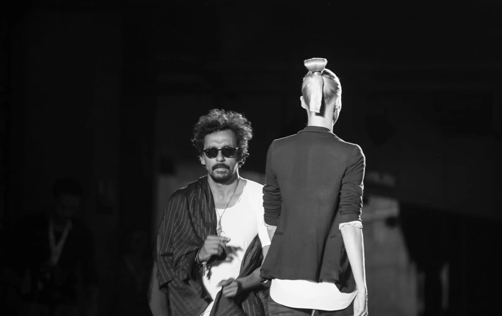 Haider Ackermann de espaldas junto a una modelo al final de su pasarela en Colombiamoda 2013, blanco y negro