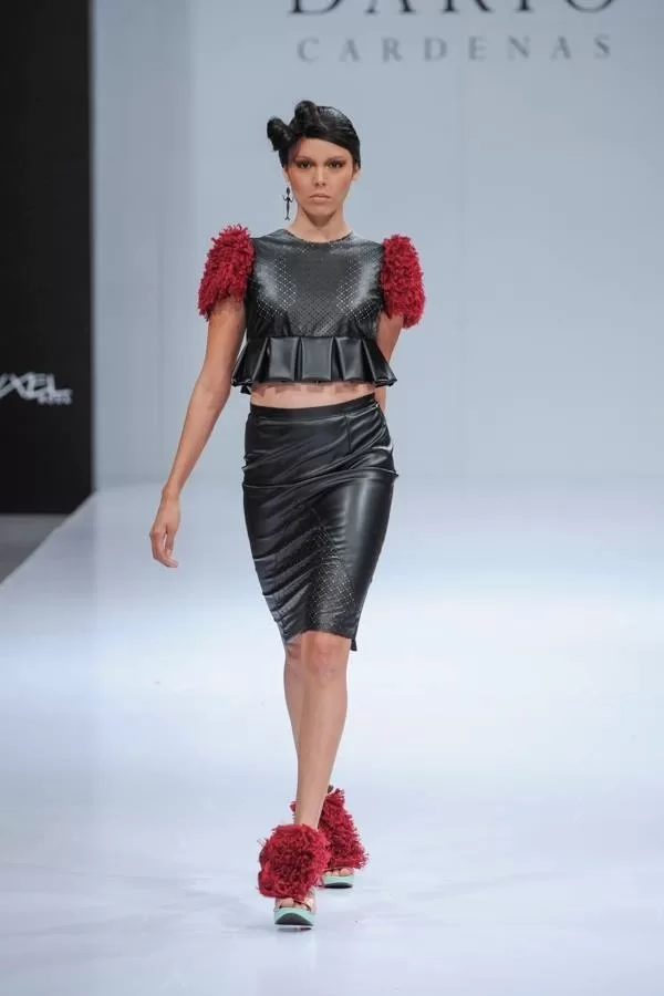 Modelo con top de plumas rojas en los hombros y falda de cuero negro de Darío Cárdenas en Ixel Moda 2013