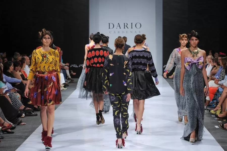 Fila de modelos de espaldas con estampados de plátanos y faldas negras al cierre de la pasarela de Darío Cárdenas