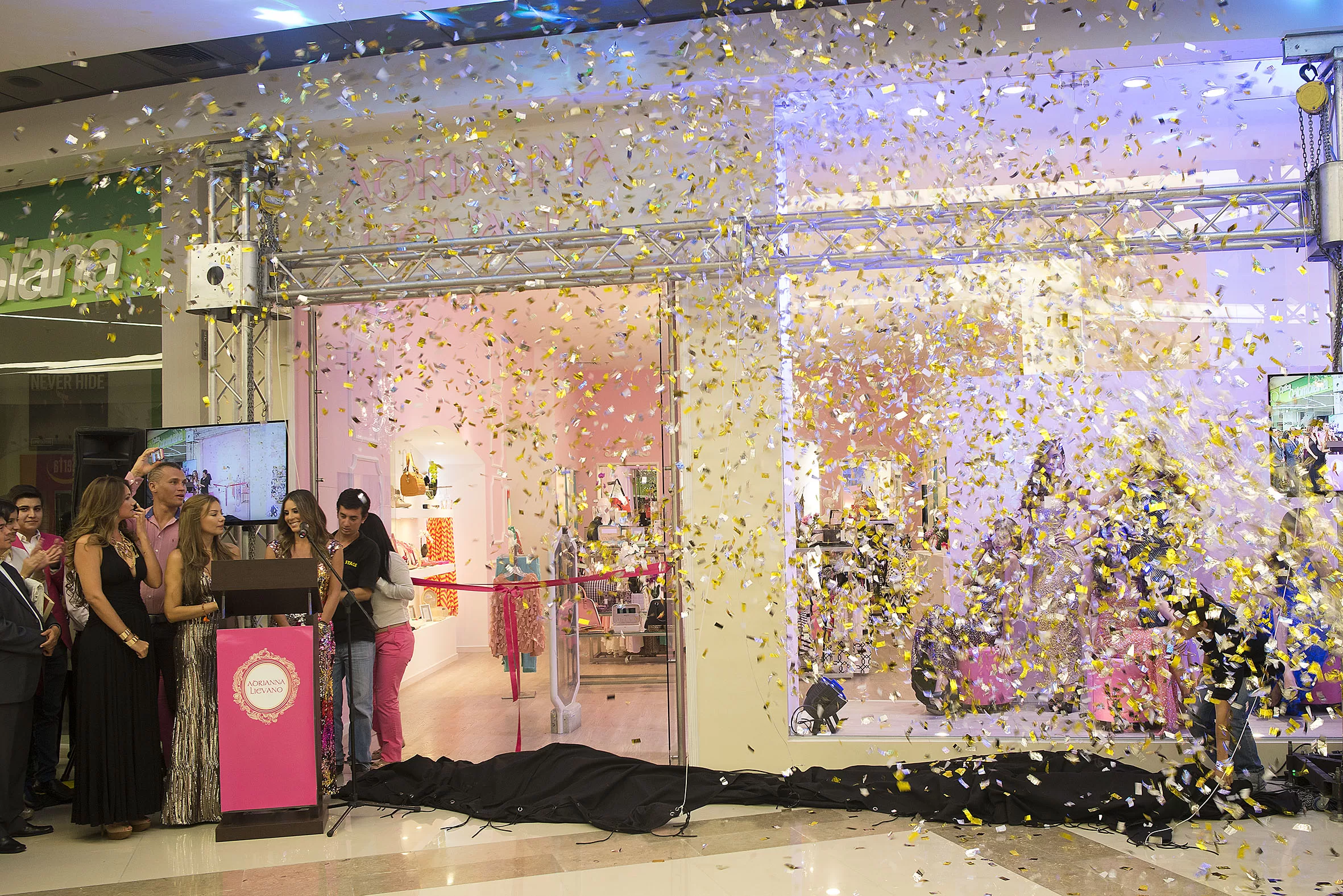 Confeti dorado cae frente a la fachada de la tienda Adriana Liévano durante su inauguración