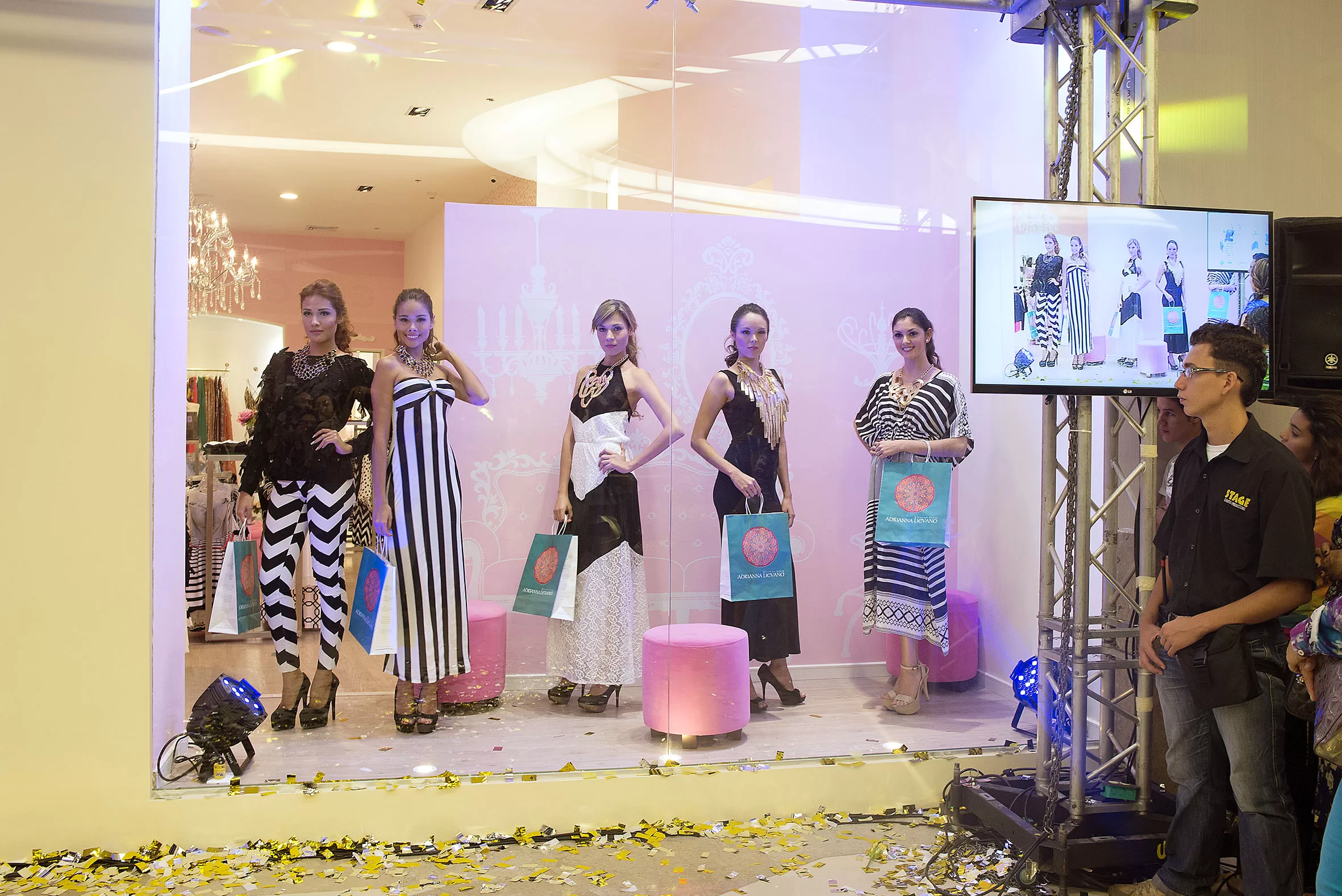 Modelos con vestidos de colores ácidos posan en la vitrina de la tienda Adriana Liévano durante la inauguración
