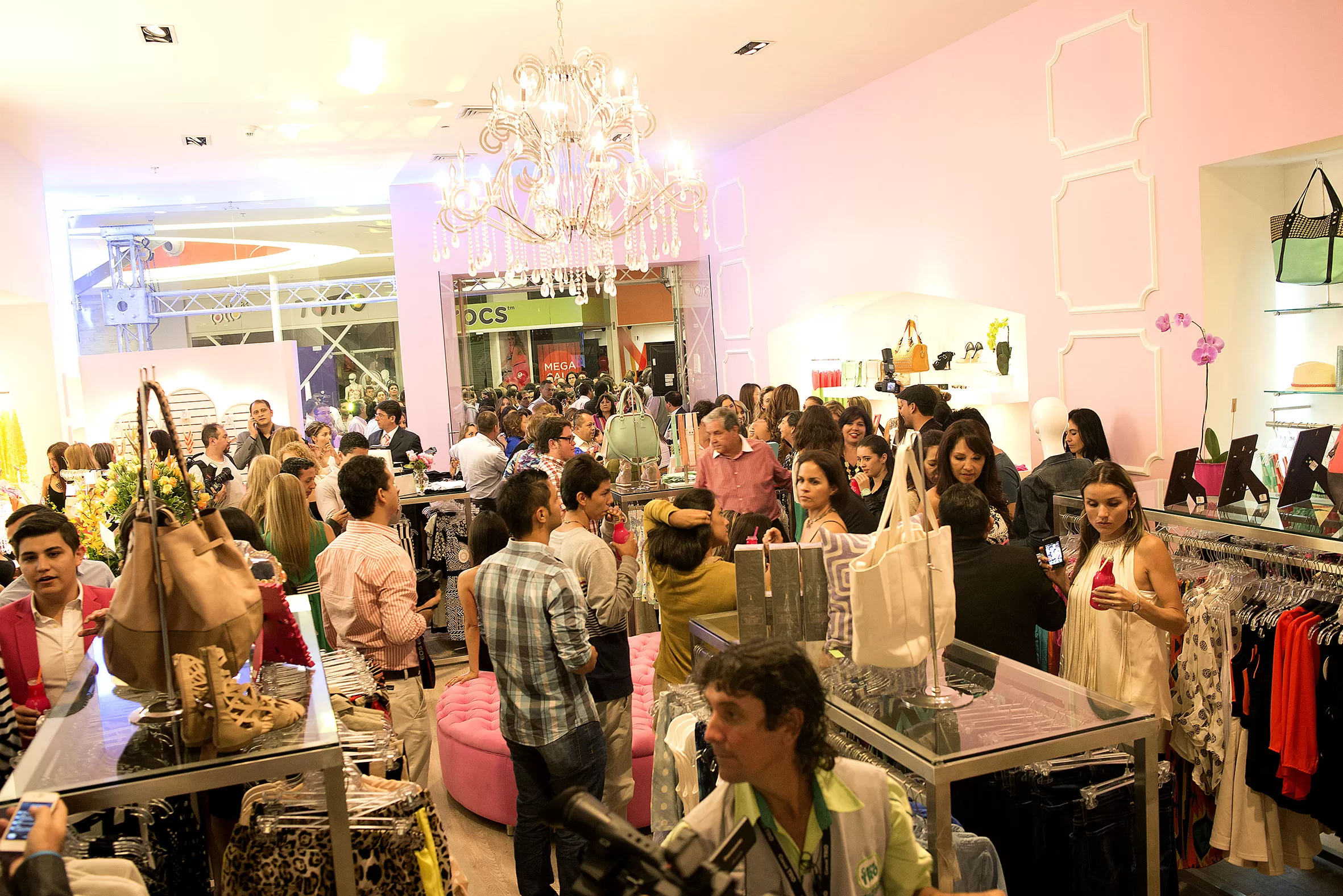 Invitados recorren la tienda rosa de Adriana Liévano con lámpara de cristal y percheros de colores