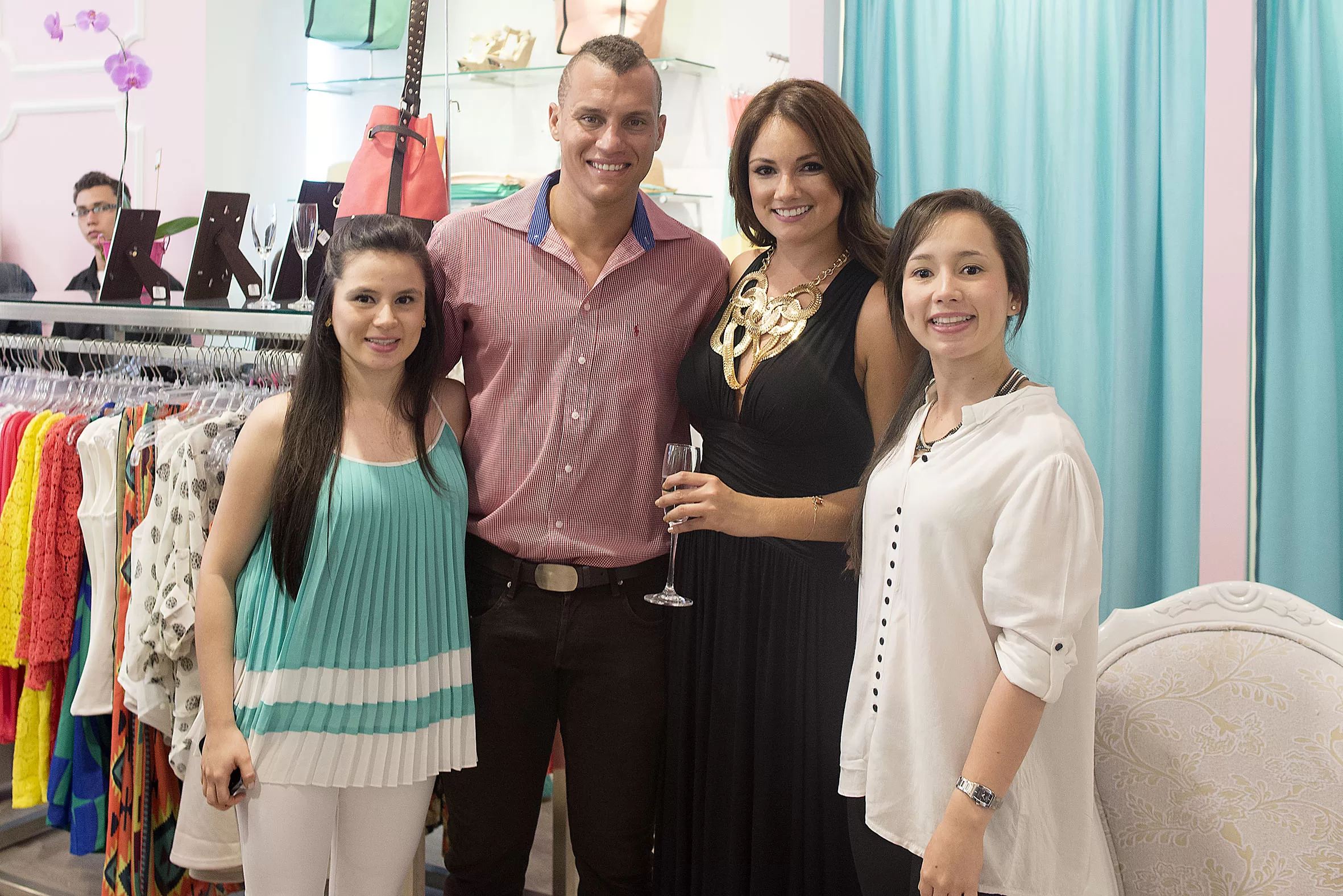 Invitados posan con copas junto a los percheros de la tienda Adriana Liévano en Parque Caracolí