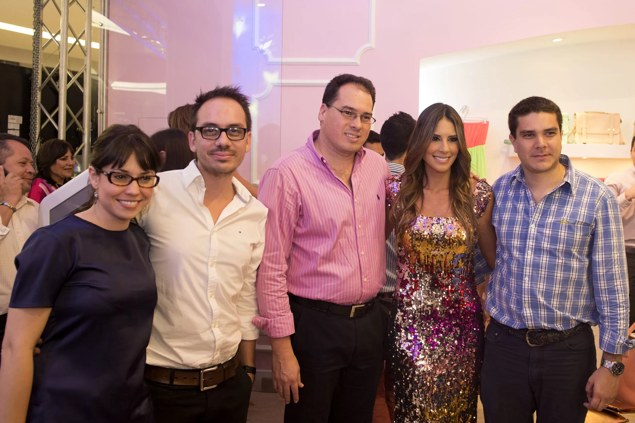 Silvia Becerra con vestido de lentejuelas morado posa con cuatro invitados en la inauguración