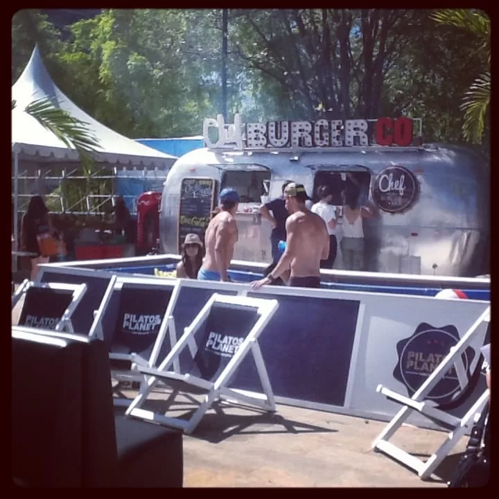 Zona de comidas con food truck de hamburguesas y sillas de playa en el stand de Pilatos Planet, Colombiamoda 2013