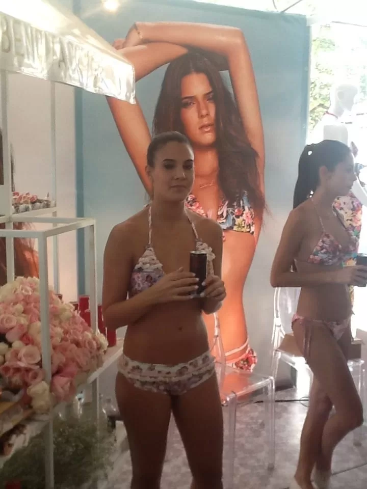 Asistente se fotografía en el espejo frente a un afiche de ropa de baño en un stand de Colombiamoda 2013