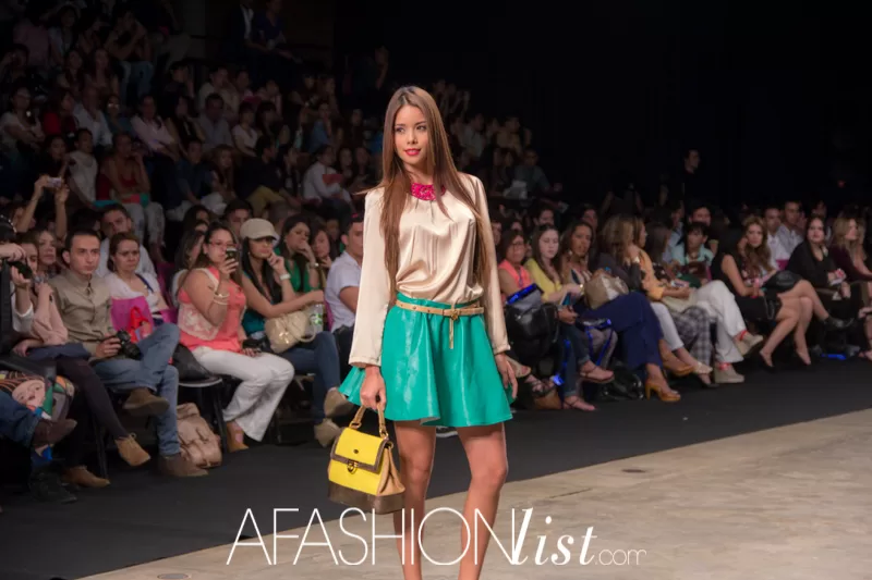Modelo con blazer beige, falda verde y bolso amarillo de SIUK ante el público del SFW 2013
