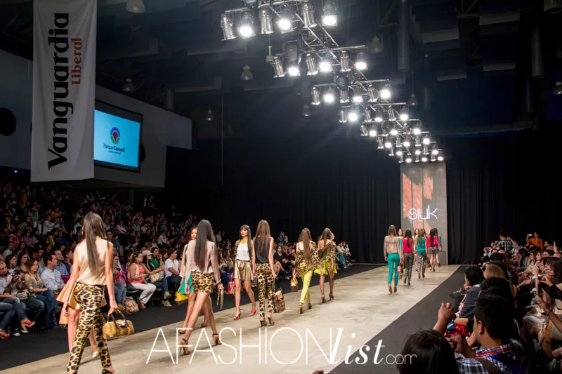 Fila de modelos de SIUK con bolsos bajo las luces de la pasarela del SFW 2013 en Cenfer
