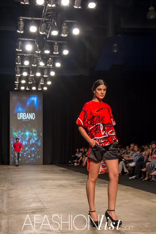Modelo con blusa roja estampada y short negro de Urbano Project bajo las luces de la pasarela del SFW 2013