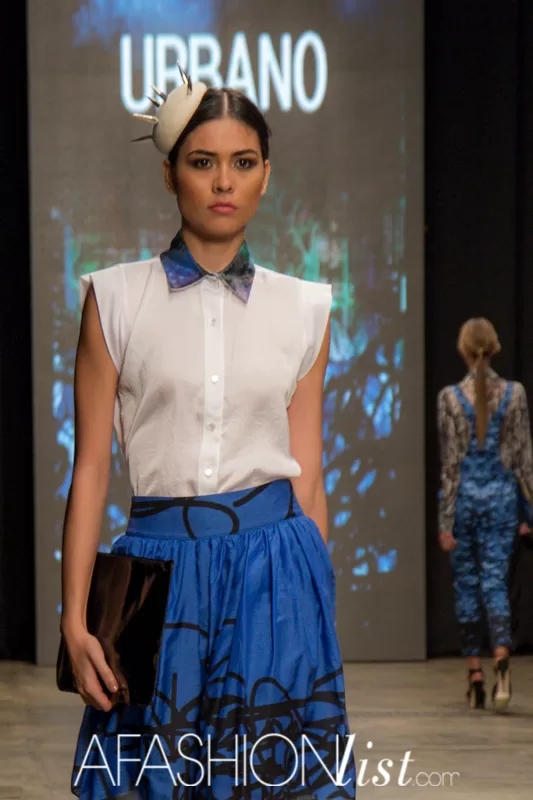 Modelo con tocado blanco, camisa blanca con cuello estampado y falda azul de Urbano Project frente a la pantalla
