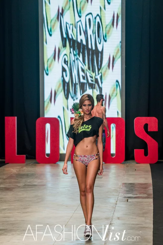 Modelo con camiseta negra Lolos y bikini estampado frente a la pantalla Ikaro Sweet en el SFW 2013