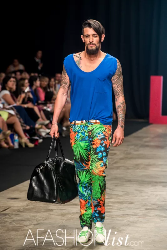 Modelo masculino con camisilla azul, pantalón con estampado tropical y bolso negro de Lolos en el SFW 2013