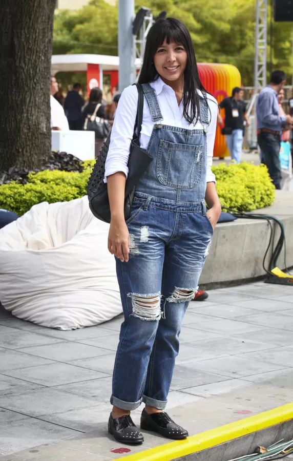 Mujer con overol de jean roto y camisa blanca en la zona exterior de Colombiatex 2014
