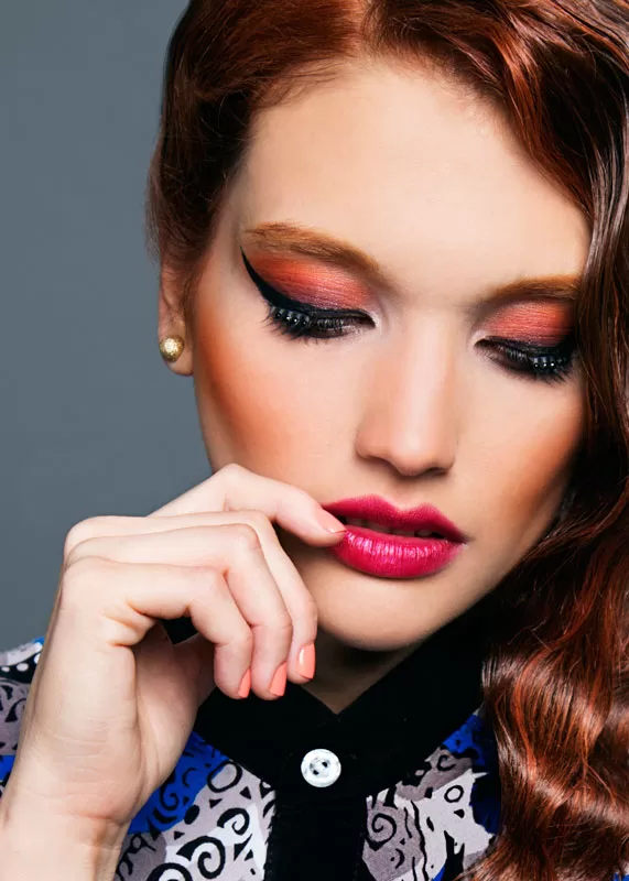 Editorial: primer plano de modelo pelirroja con sombra naranja y labios fucsia