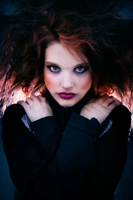 Editorial: modelo con cabello despeinado y suéter negro sobre fondo oscuro