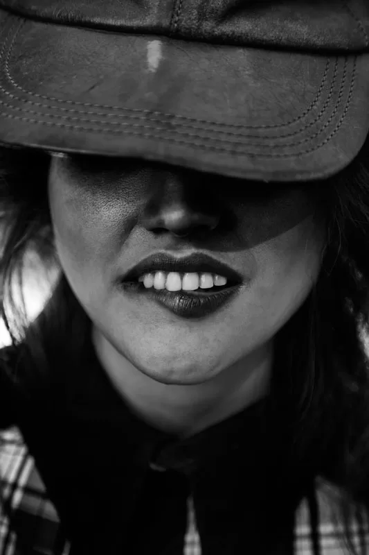 Editorial: fotografía en blanco y negro de una sonrisa bajo una gorra