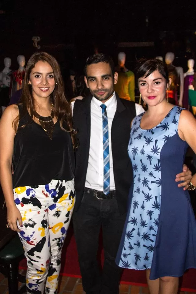 Tres invitados con pantalón estampado, traje y vestido de palmeras posan en el lanzamiento