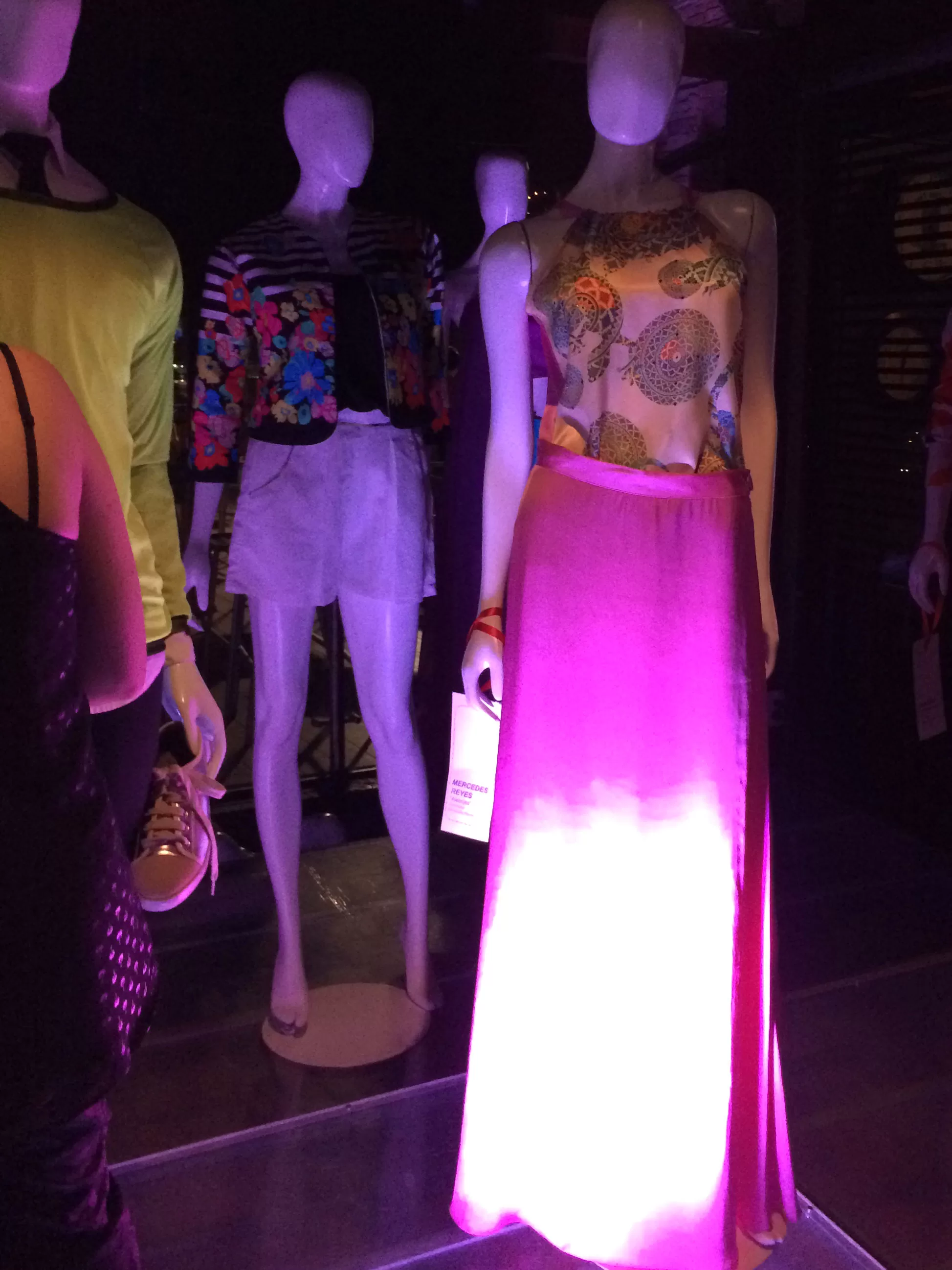 Maniquí con falda larga rosa degradé y top estampado bajo luces moradas