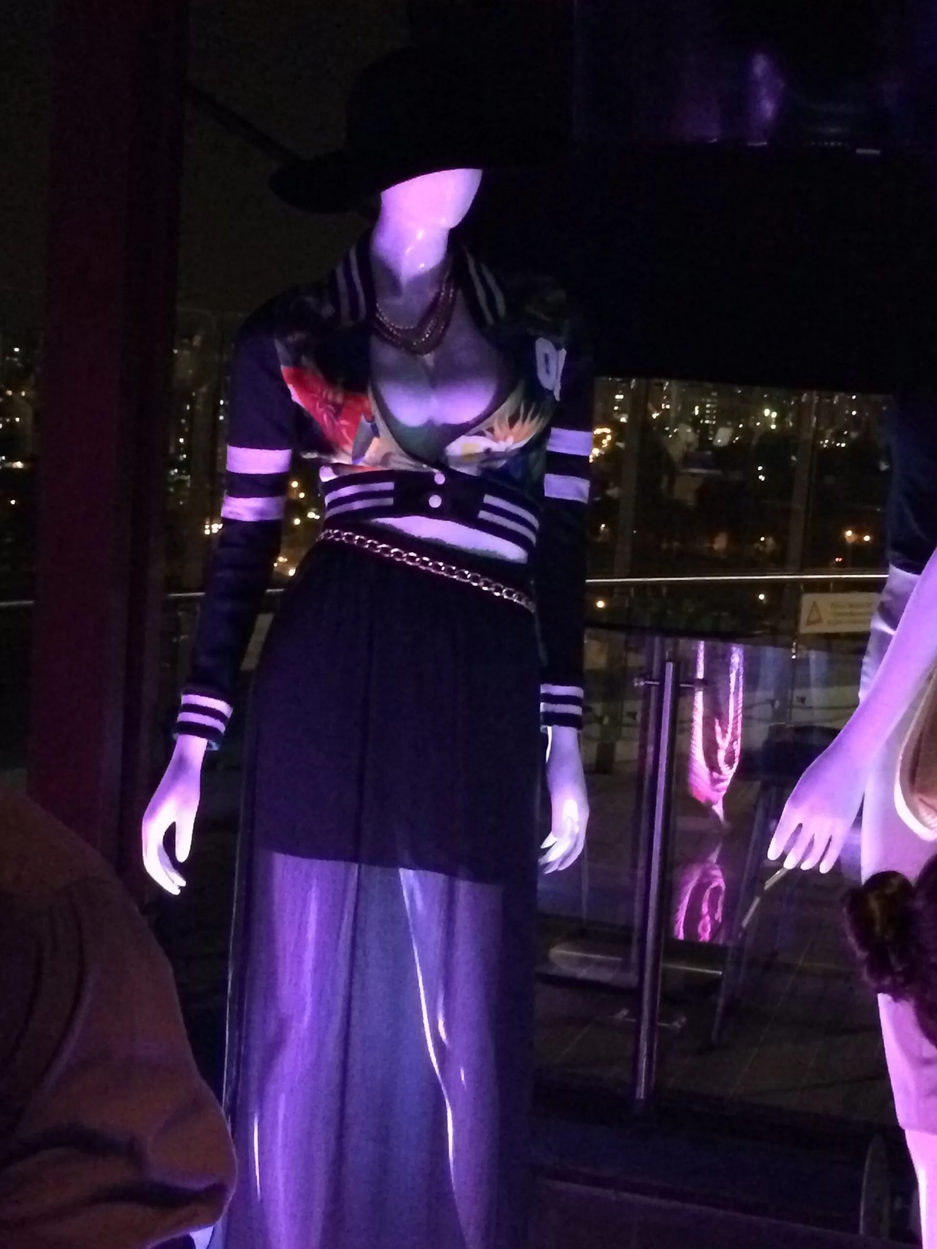 Maniquí con vestido negro de rayas y estampado bajo luces azules
