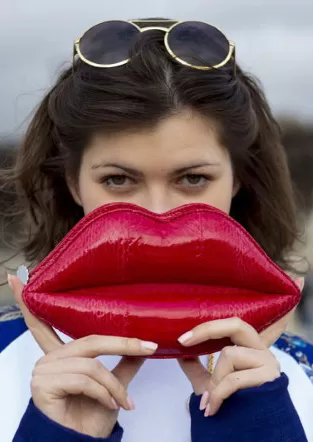 Clutch con forma de labios rojos frente al rostro, street style